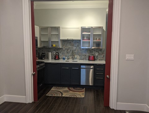 a kitchen with black cabinets and white appliances and a rug